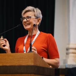 Person behind a podium, giving a presentation