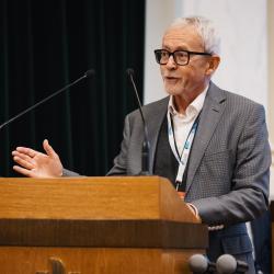 Person behind a podium, giving a presentation