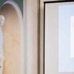 Person behind a podium, giving a presentation