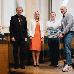 People on stage, receiving a gift, in an auditorium
