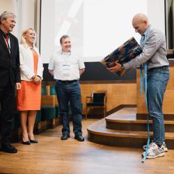 People on stage, receiving a gift, in an auditorium