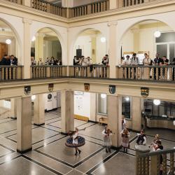 Music band with dancers in a building hall, people listening from the second floor