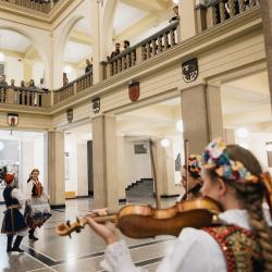 Music band with dancers in a building hall, people listening from the second floor