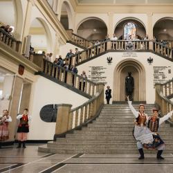 Dancers in a building hall, people watching from the second floor