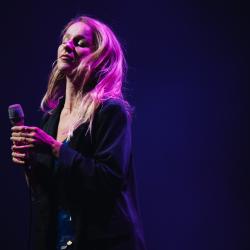 Singer on a dark stage, lit up by stage lights