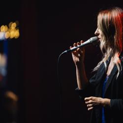 Singer on a dark stage, lit up by stage lights