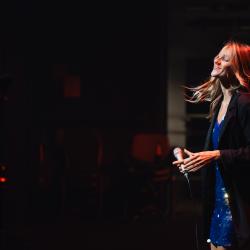 Singer on a dark stage, lit up by stage lights