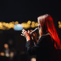 Singer on a dark stage, lit up by stage lights