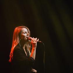 Singer on a dark stage, lit up by stage lights
