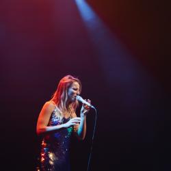 Singer on a dark stage, lit up by stage lights