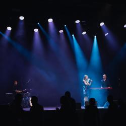 Music band on a dark stage, lit up by stage lights
