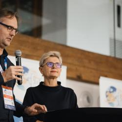 Two people, one talking to a microphone