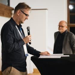 Person on a stage, at a podium, talking to a microphone
