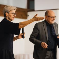 Two people, one talking to a microphone