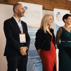 Three people on stage in a banquet hall